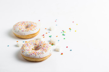 Fresh tasty donuts and sweet multicolored decorative candy on a white background. Bakery concept, fresh pastries, delicious breakfast.