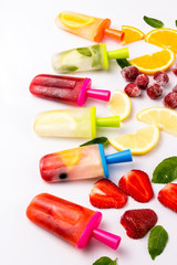 Multicolored bright fruit popsicle with strawberry, cherry, lemon, orange, lemon and mint and slices fresh fruit on a light white background