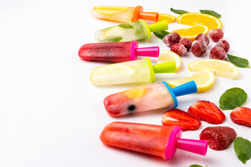 Multicolored bright fruit popsicle with strawberry, cherry, lemon, orange, lemon and mint and slices fresh fruit on a light white background