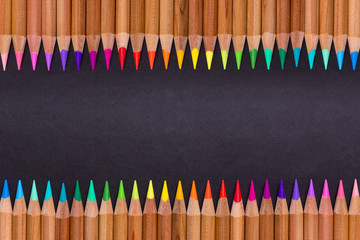 Colorful pencils arranged in row on black background