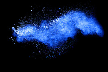 Blue color powder explosion cloud on black background.Closeup of Blue dust particles exhale on dark background.