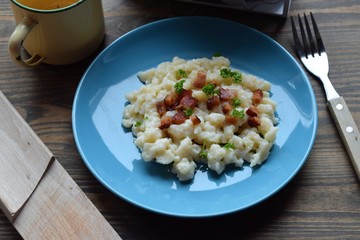 Slovak traditional potato gnocchi with sheep cheese and bacon,wooden table