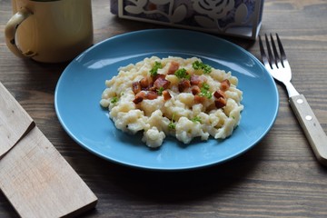Slovak traditional potato gnocchi with sheep cheese and bacon,wooden table