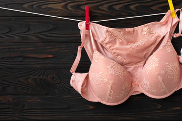 Women's lace sexy underwear of red, pink color: bra and panties. Women'e clothes hanging on rope on grey background 