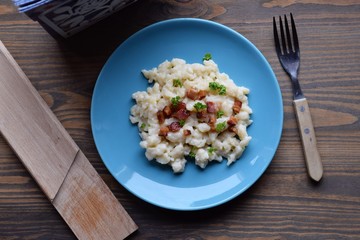 Slovak traditional potato gnocchi with sheep cheese and bacon,wooden table