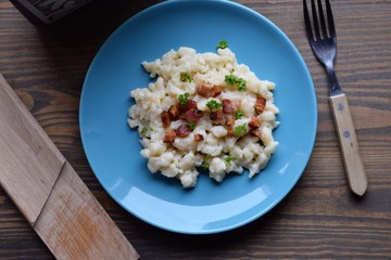 Slovak traditional potato gnocchi with sheep cheese and bacon,wooden table