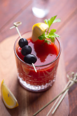 Cocktail Bloody Mary with ice, salt and snacks in glass on a wooden table