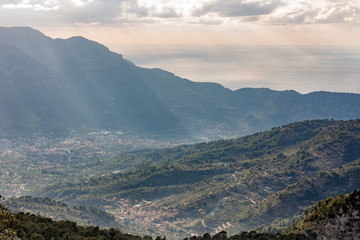 Sonnenstrahlen breiten sich durch einen Wolkenbruch auf das Tal der Berge aus