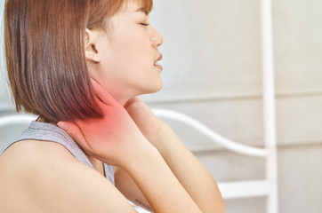 Fototapeta premium Asian girl in gray dress is in a white bedroom with neck pain.