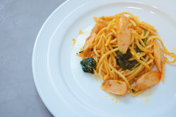 Spaghetti with sausage, Stir-fried sausage, Italian food.Spaghetti with red sauce, white plate on the table in the morning restaurant.