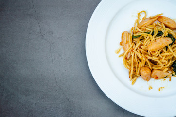 Spaghetti with sausage, Stir-fried sausage, Italian food.Spaghetti with red sauce, white plate on the table in the morning restaurant.