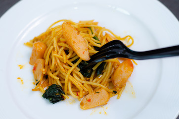 Spaghetti with sausage, Stir-fried sausage, Italian food.Spaghetti with red sauce, white plate on the table in the morning restaurant.