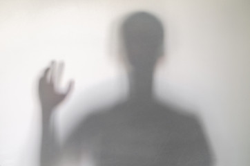 Man waving or rising his hand behind curtain.