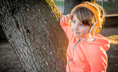 young girl is listen music with headphone to the park