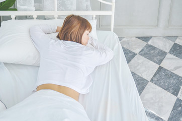 Beautiful woman sleeping in the bedroom..Woman lying face down on the bed.He slept with sleep..A woman wearing a pajama sleep on a bed in a white room in the morning.Do not focus on objects.Warm tone.