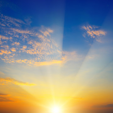 Scenic sunset with sun rays against bright blue sky