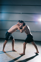 Fototapeta premium muscular barefoot mma fighter clinching sportive opponent