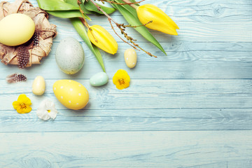 Osternest und Ostereier mit Tulpen auf Holzhintergrund in blau, Osterkarte