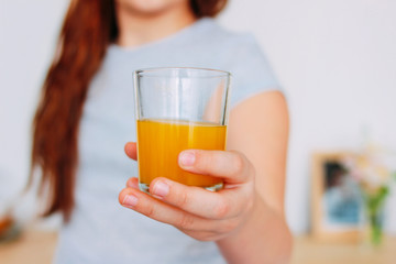 The girl holding glass of orange juice in hand, selective focus