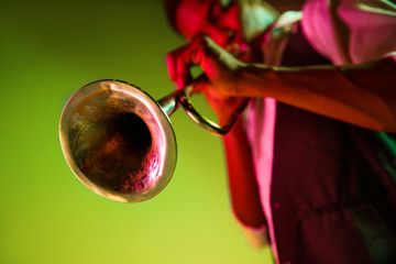 African American handsome jazz musician playing trumpet in the studio on a neon background. Music...