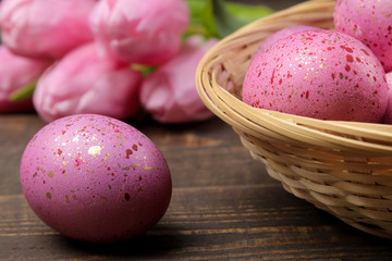 Easter. Pink easter eggs in basket and tulips on brown wooden table. Happy easter. holidays.