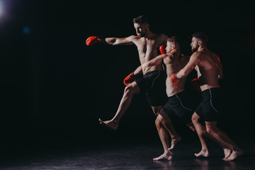 multiple exposure of strong shirtless muscular mma fighter in boxing gloves doing punch in jump