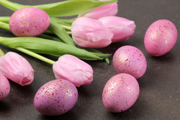 Easter. Pink Easter eggs and flowers tulips on a dark background. Happy easter. holidays.