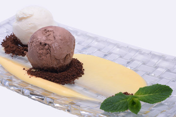  Scoop balls of vanilla and chocolate ice cream with chocolate crumb. On a crystal plate isolated on white background. Close up