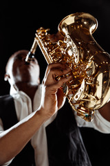 African American handsome jazz musician playing the saxophone in the studio on a black background....