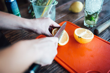 Barman prepares fruit alcohol cocktail based on lime, mint, orange, soda