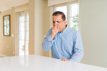 Middle age man sitting at home feeling unwell and coughing as symptom for cold or bronchitis....