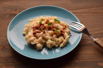 Slovak traditional potato gnocchi with sheep cheese and bacon,wooden table