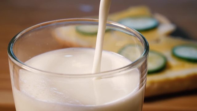 Pours up a glass of milk for breakfast