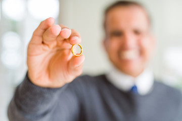 Close up of middle age man holding a engagement ring and smiling to the camera