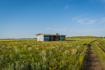Abandoned painter's house on a green field  on a blue sky background