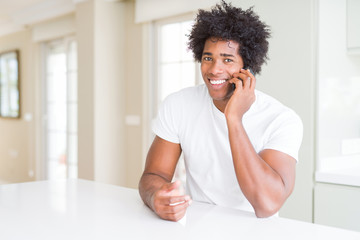 African American business man talking on the phone with a happy face standing and smiling with a confident smile showing teeth