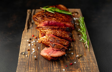 Beef steak, herbs and spices on a cutting board against a background of stone