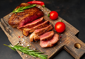 Beef steak, herbs and spices on a cutting board against a background of stone