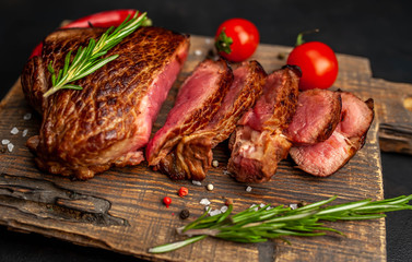 Beef steak, herbs and spices on a cutting board against a background of stone