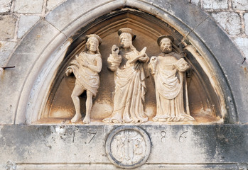Jesus Christ, St. John the Baptist and St. Nicholas with a stick, portal of Saint Luke Church in Dubrovnik, Croatia 