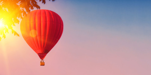 Fototapeta na wymiar Red balloon in the sky. Aerostat. People in the basket. Fun. Summer entertainment. Romantic adventures. Modern toned photo. Retro colors.