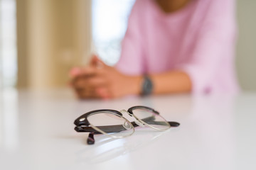 Close up of eye glasses over white table with young woman at the background