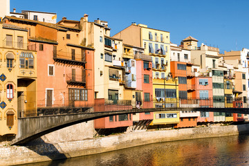 Fototapeta na wymiar Colorful houses and Gomez bridge against blue sky in Girona, Catalonia, Spain. Selective focus on buildings