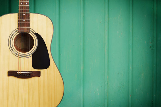 Acoustic guitar on green color metal wall 