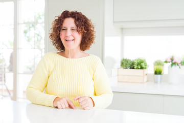 Beautiful senior woman wearing yellow sweater winking looking at the camera with sexy expression,...