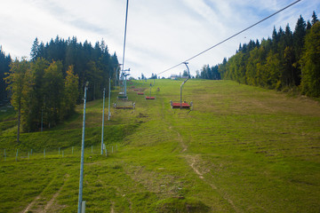 Emtpy chairlift in ski resort. Mountains and hills with in Summer with green trees