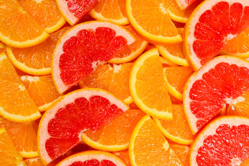 Fototapeta na wymiar Slices of oranges and a grapefruits as a background.
