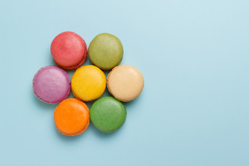 Fototapeta na wymiar Overhead view of bright colorful macaroons on blue background with copy space