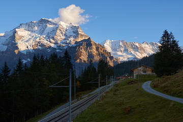 Sunset view of Jungfrau mountain with old style wooden house at foreground in Lauterbrunnen in Switzerland.