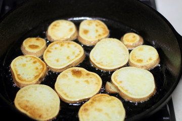 Sweet potato chips cooking in a cast iron pan.